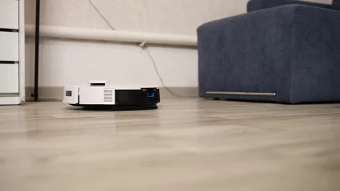 Smart robot vacuum cleaner automatically cleaning the laminate floor of a Stock Footage 346318538