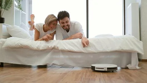 Smart robot vacuum saving man and woman from tedious home work Stock Photos
