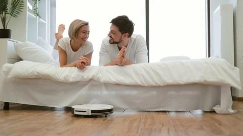 Smart robot vacuum saving man and woman from tedious home work Stock Photos