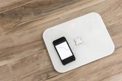 Smart scale standing on a floor connected to smartphone Stock Photos