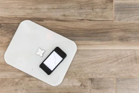 Smart scale standing on a floor connected to smartphone Stock Photos