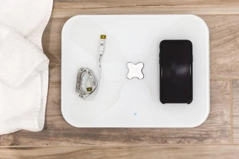 Smart scale standing on a floor connected to smartphone Stock Photos
