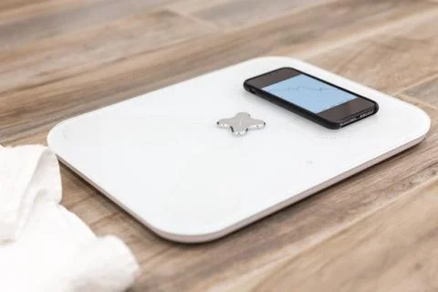 Smart scale standing on a floor connected to smartphone Foto stock