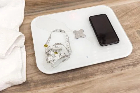 Smart scale standing on a floor connected to smartphone Stock Photos