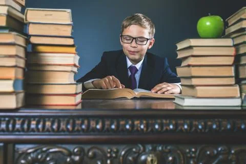 Smart school boy reading a book at library Stock Photos