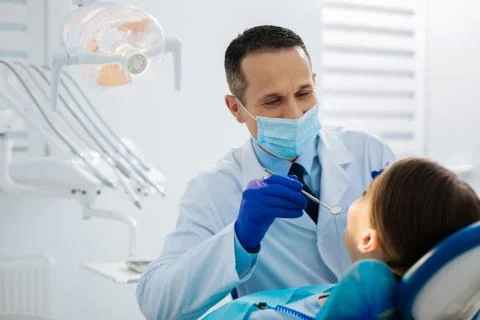 Smart skillful dentist using a mirror Stock Photos