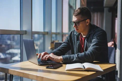 Smart software developer sitting at desktop in coworking space with laptop an Stock Photos