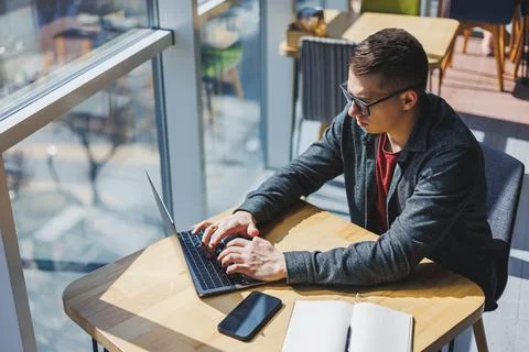 Smart software developer sitting at desktop in coworking space with laptop an Stock Photos