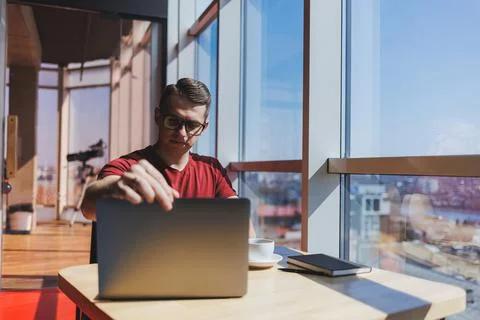 Smart software developer sitting at desktop in coworking space with laptop an Stock Photos