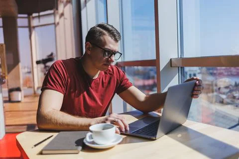 Smart software developer sitting at desktop in coworking space with laptop an Stock Photos