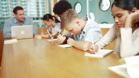 Smart student doing test while teacher using laptop analysis data. Edification Stock Footage 281113082