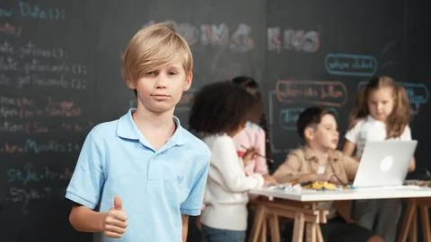 Smart student showing thumb while diverse friend working at board. Erudition. 스톡 사진