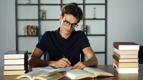 Smart student sitting at table and writing on notebook. Preparing before the Stock Footage 93241192