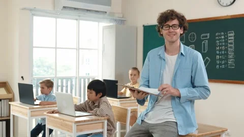 Smart teacher checking document and looking at camera at classroom. Pedagogy. Stock Footage 272171069