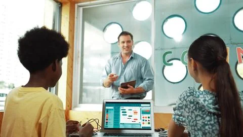 Smart teacher hold tablet while back view student learning code. Edification. Stock Photos