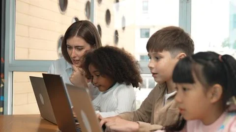 Smart teacher teaching and looking student using laptop at classroom. Erudition. Stock-Fotos