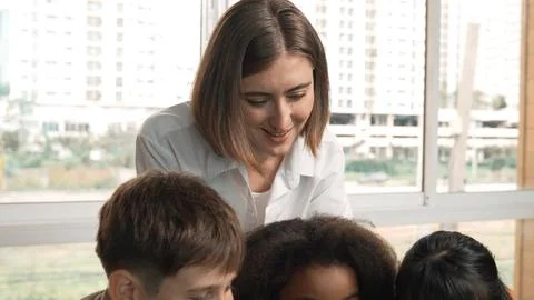 Smart teacher teaching and looking student using laptop at classroom. Erudition. Stock-Fotos