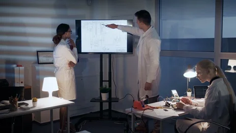 Smart team of Electronics Development Engineers discussing something on a big TV Stock Footage 112868680
