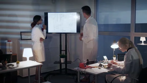 Smart team of Electronics Development Engineers discussing something on a big TV Видео 151959232