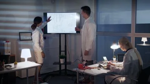 Smart team of Electronics Development Engineers discussing something on a big TV 스톡 사진