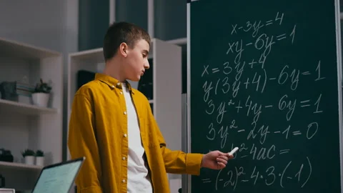 Smart teenager explaining the solution to algebra equation near chalkboard Stock Footage 251805536