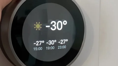 A Smart Thermostat during temperatures under -30 degrees and a person warming up Stock Footage 167578294