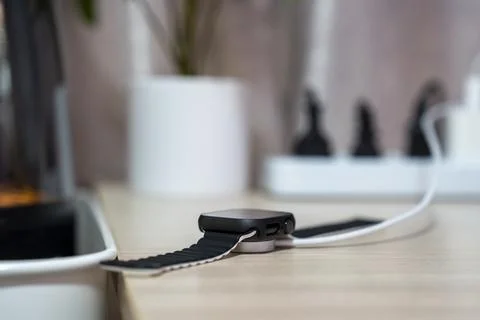 Smart watch is charging on the table Stock Photos