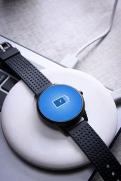 Smart watch on wireless charging with on-screen charging indicator. At the de Stock Photos