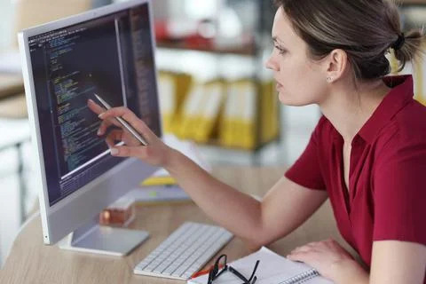 Smart woman checks code of program pointing pen to screen Photos