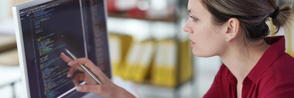 Smart woman checks code of program pointing pen to screen Stock Photos