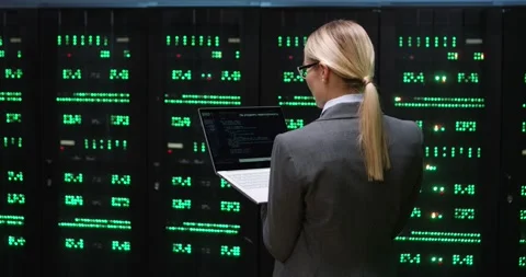 Smart woman programmer in suit standing in server room holding laptop writes new Video stock 148440912
