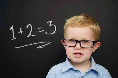 Smart young boy stood infront of a blackboard Stock Photos