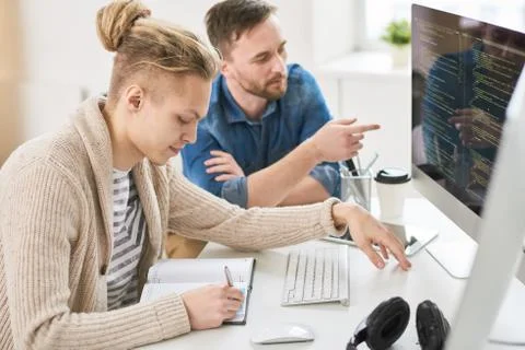 Smart young colleagues discussing programming code 库存照片