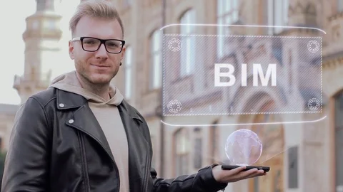 Smart young man with glasses shows a conceptual hologram BIM Stock Footage 99136557