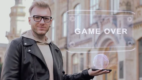 Smart young man with glasses shows a conceptual hologram Game Over Stock Footage 99352638
