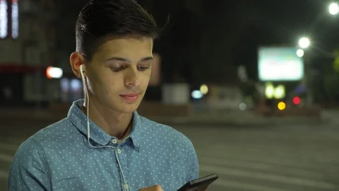 Smart young man is surfing the net and standing in illuminated street at night Stock-Footage 95981735