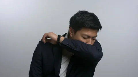 Smartly dressed Asian man coughing into elbow Stock Footage