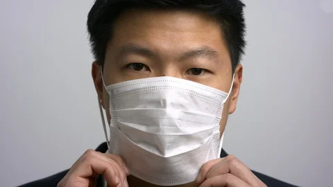 Smartly dressed Asian man putting on face mask Stock Footage 129843892