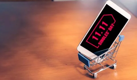 Smartphone with 11.11 message on screen inside a small shopping cart, singles Stock Photos