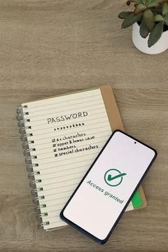 Smartphone with Access Granted Message Resting on Password Notebook Stock Photos