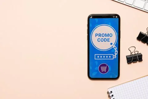 Smartphone with activated promo code and stationery on beige table, flat lay. Stock Photos