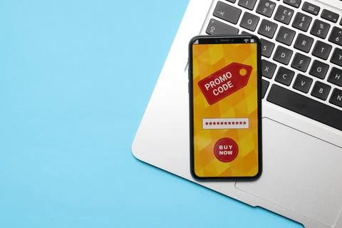 Smartphone with activated promo code and laptop on light blue background, t.. Stock Photos