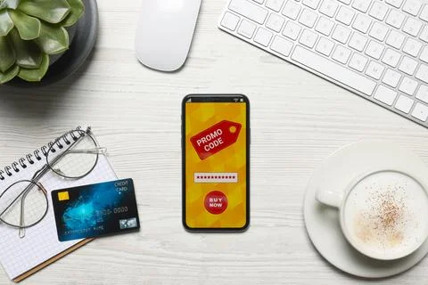Smartphone with activated promo code on wooden table, flat lay Stock Photos