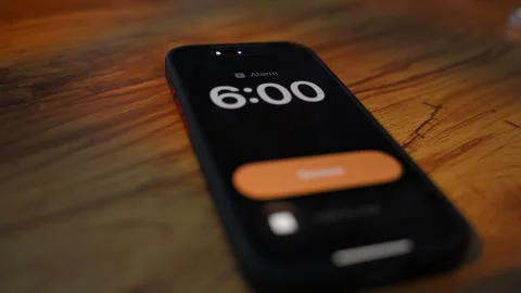 Smartphone alarm clock showing 6:00 on screen. morning wake up concept with Stock Footage 334022860