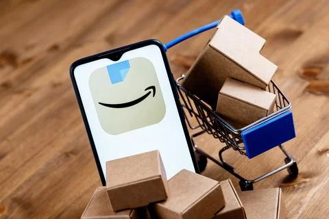 Smartphone with Amazon app logo on screen, shopping cart and parcels Foto stock