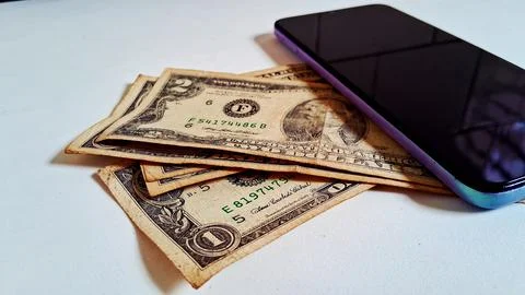 Smartphone and cash notes on table. Mobile payment and financial transaction Stock Photos