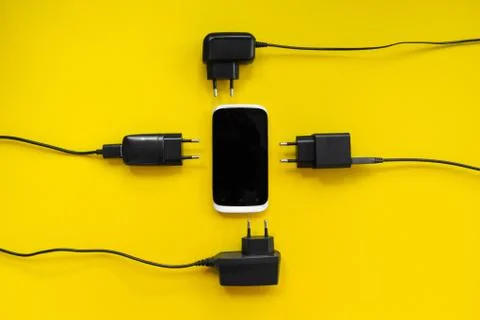 Smartphone and chargers around on a yellow background, concept. Stock Photos