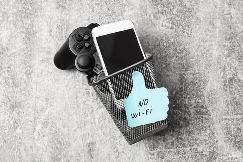 Smartphone and game controller in trash bin with no wi-fi note Stock Photos