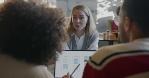Smartphone application developers talking and using laptop computer focused on Stock Footage 271624670