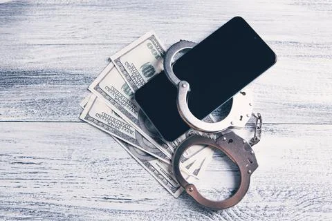 Smartphone on banknotes with handcuffs Stock Photos